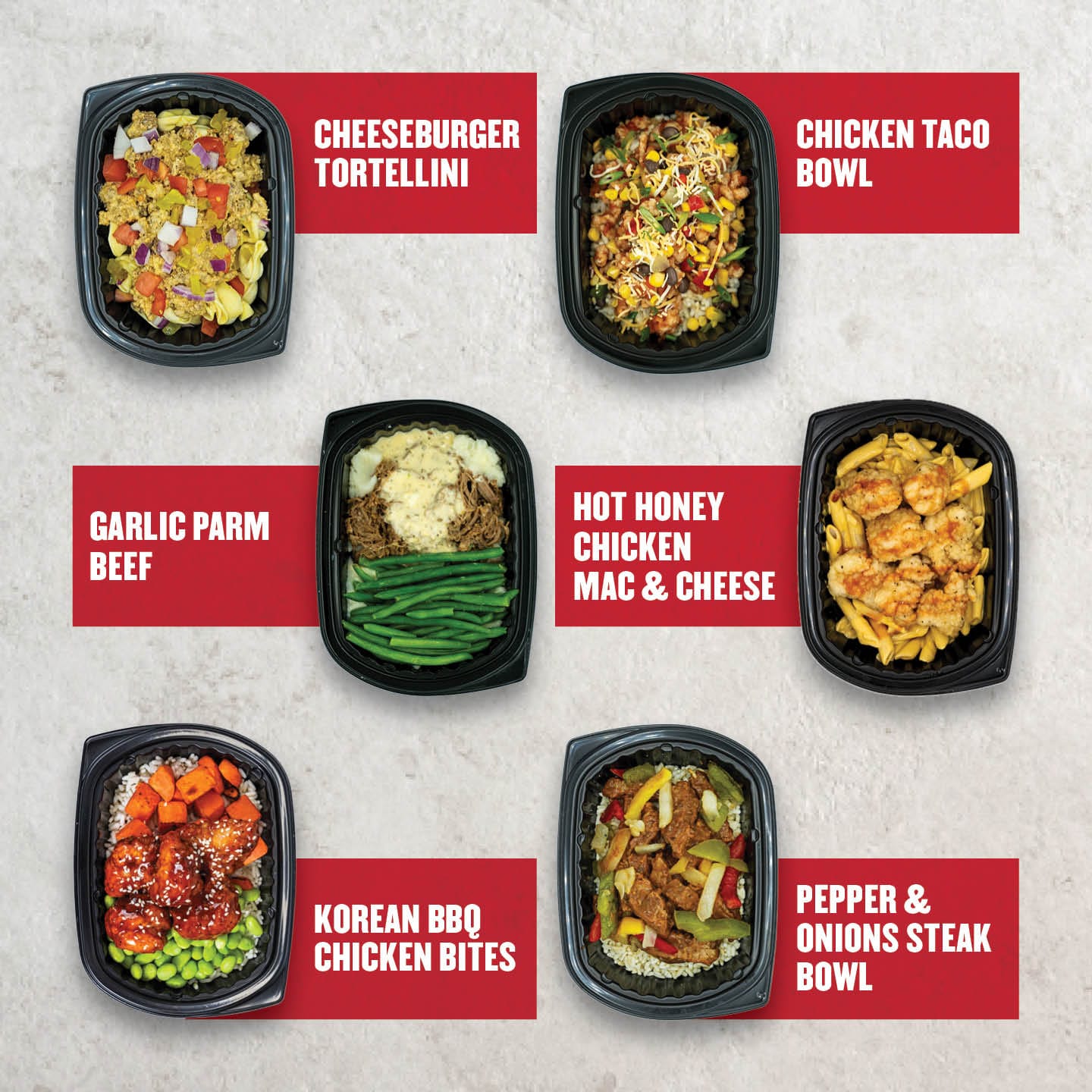 An assortment of Clean Eatz Kitchen meals, featuring cheeseburger tortellini, chicken taco bowls, hot honey mac and cheese, Korean BBQ chicken bites, and pepper & onion steak bowls, all served in black meal containers.